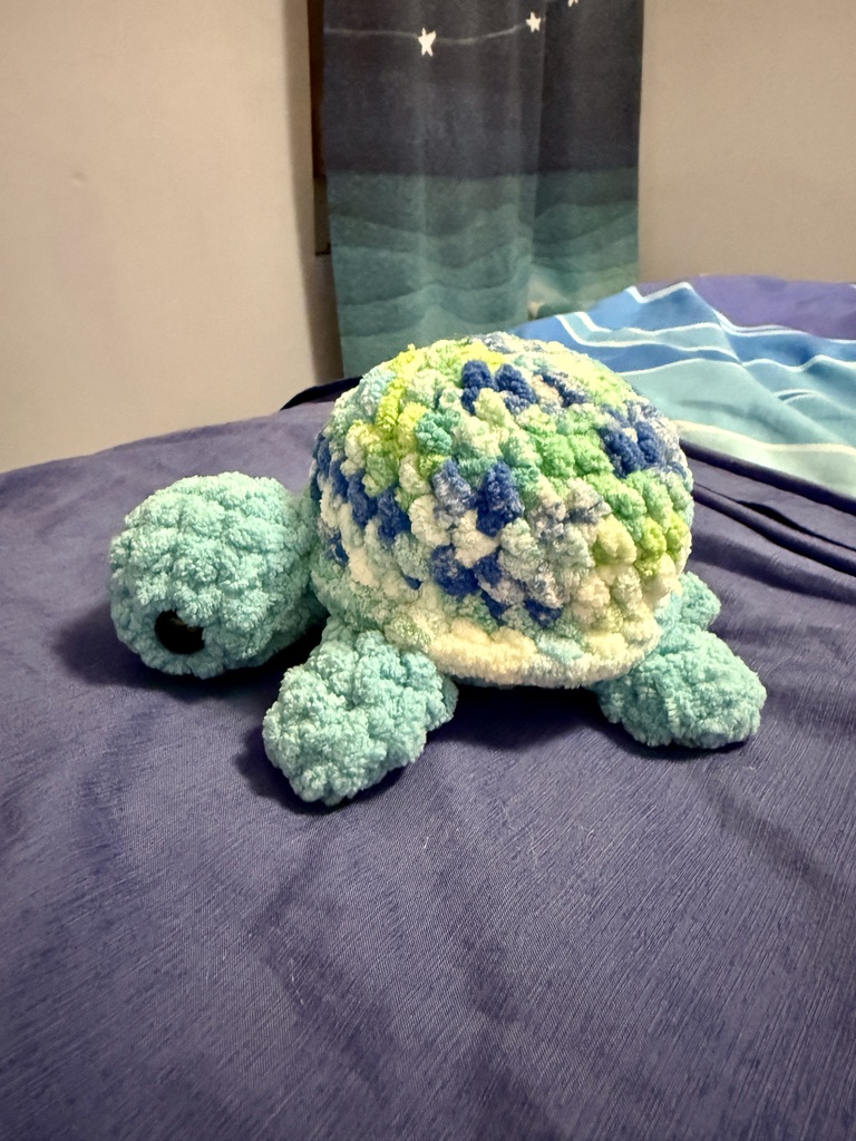 Jerry the Tie-Dye Turtle crochet amigurumi plushie toy handmade craft finished object made with green, blue, and white tie-dye yarn for the shell and light blue yarn for the head and body