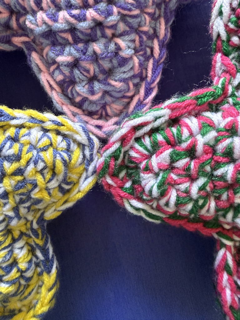 Star points of 3 Marbled Star handmade crocheted amigurumi pillow plushies, made by marling 3 strands of yarn of different colors together