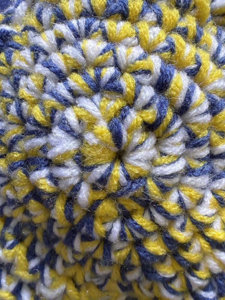 Marbled Star crochet plush pillow close-up with 3 strands of yarn marled together: Starry Night color palette (yellow, blue, and white)