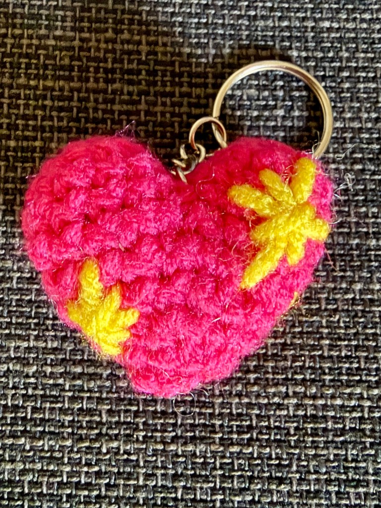 Close-up of a crocheted pink sparkle heart emoji keychain