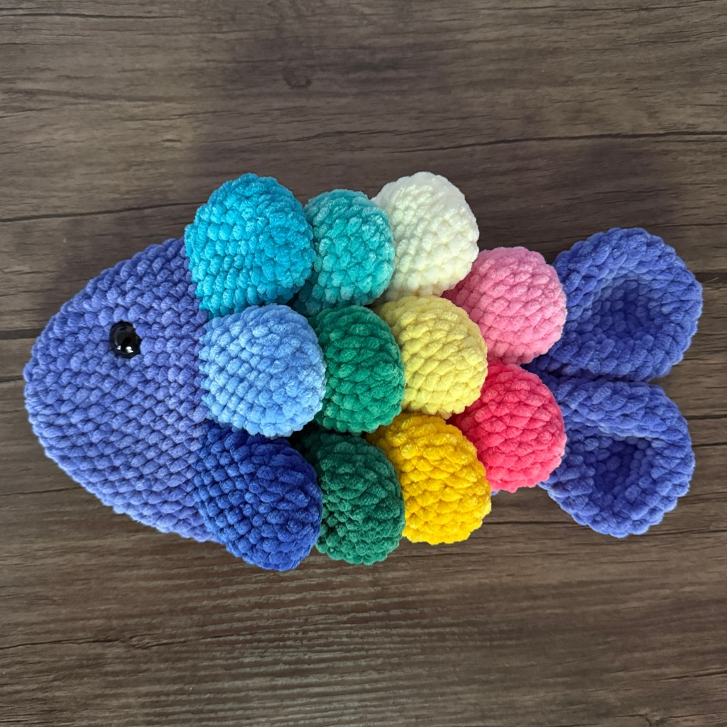 Crocheted rainbow fidget fish made with Parfait Chunky chenille yarn: periwinkle body and multicolored scales